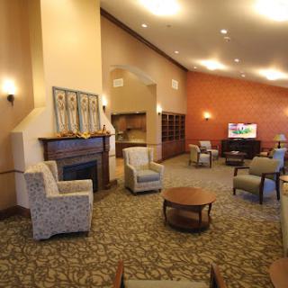 A cozy lounge area featuring comfortable seating, a fireplace, and warm lighting.