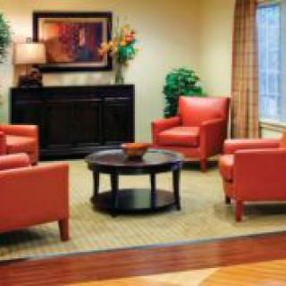 A cozy living room with red chairs arranged around a round coffee table.