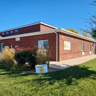 A sunny day view of a brick building surrounded by greenery.