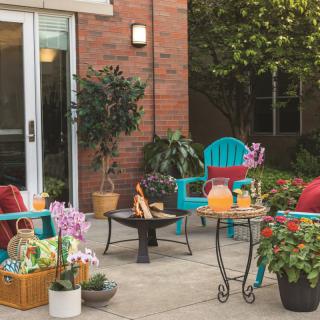 A cozy patio setup with colorful chairs, plants, and a fire pit creating an inviting outdoor space.
