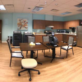 A cozy office breakroom featuring a dining area with a table and chairs, equipped kitchen appliances, and a welcoming atmosphere.