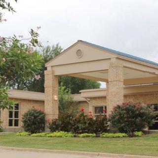 A building entrance with landscaped greenery and a clear sky backdrop.