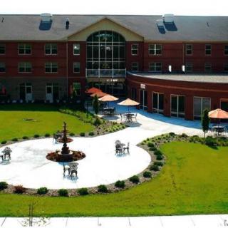 A courtyard with a central fountain, surrounded by a well-maintained lawn and seating areas.