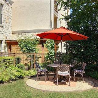 Outdoor patio set with a red umbrella and chairs in a garden setting.
