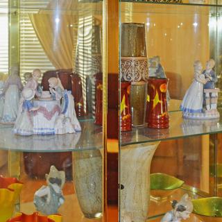 A showcase of porcelain figurines and antiques in a glass display case.