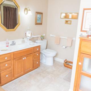 A clean and well-organized bathroom with a wooden vanity, mirror, and toilet.