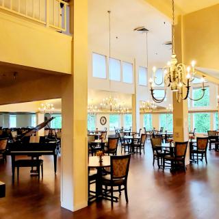 A spacious dining area with elegant chandeliers and neatly arranged tables and chairs.