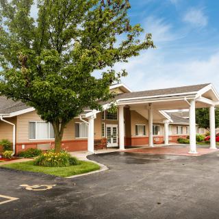 A building with a covered entrance and surrounding landscaping on a clear day.