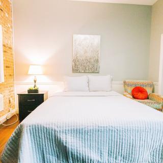 A cozy bedroom with a neatly made bed, side table lamp, and wall artwork.