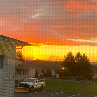 A picturesque sunset painting the sky in vibrant hues of orange, viewed through a screen.