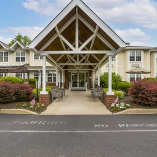 A welcoming building entrance with a covered porch and landscaped surroundings.