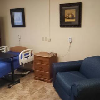 A hospital room with a patient bed, side table, and a chair.