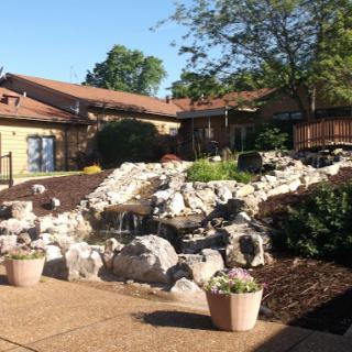 A serene outdoor space featuring a landscaped garden with a water feature and surrounding greenery.