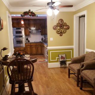 A cozy open floor plan with a dining area leading into a kitchen, featuring wood flooring and homey decor.