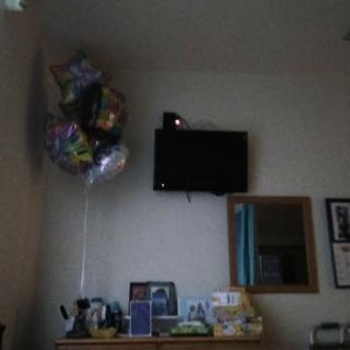 A cozy room featuring colorful balloons, a television on the wall, and a reflection in the mirror.
