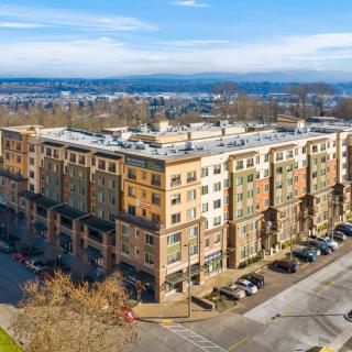 Aerial view of a multi-story apartment building with a parking lot in an urban setting.