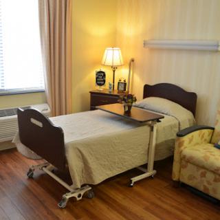 A cozy hospital room featuring a bed, side table, and comfortable chair.