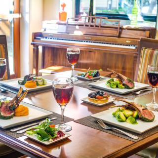 A beautifully set dining table with gourmet meals and glasses of red wine, ready for an elegant meal.