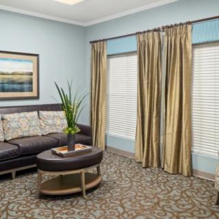 A cozy living room with a sofa, stylish curtains, and a coffee table on a patterned carpet.