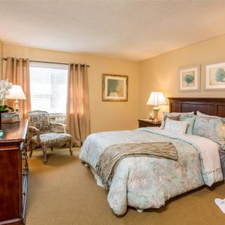 A cozy bedroom with a well-made bed, stylish furniture, and warm lighting.