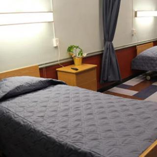 A neatly arranged room with two twin beds, cozy lighting, and a small plant on a bedside table.