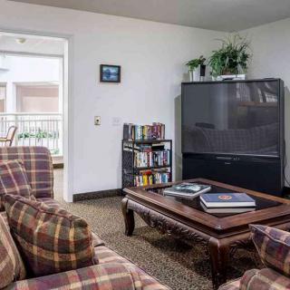 Cozy living room with a large TV, plaid sofas, and a wooden coffee table.