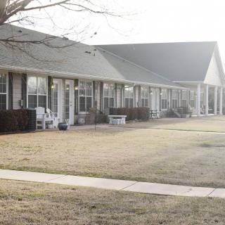 A row of residential buildings with porches and a neatly maintained lawn in the foreground.