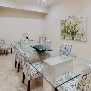 A modern dining room with a glass table and patterned chairs, accented by wall art.