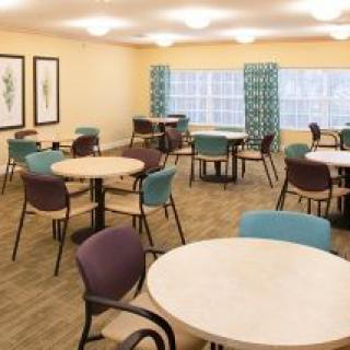 An empty dining room with round tables and colorful chairs.