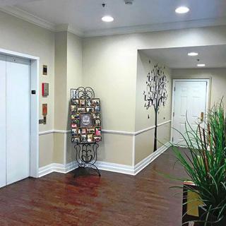 A well-lit hallway featuring an elevator, a brochure rack, and decorative plants.