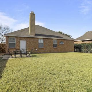 A suburban brick house with a spacious backyard and chimney.
