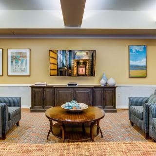 A cozy living room with comfortable seating, a wall-mounted TV, and decorative artwork.