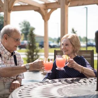 An elderly couple enjoying refreshing drinks together outdoors.