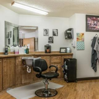 A cozy barbershop interior with a styling chair and mirrored counter.