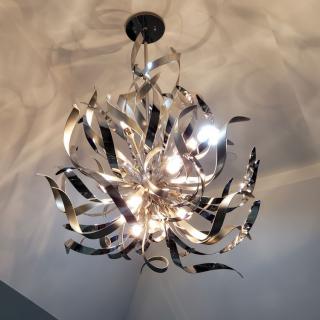 A modern metallic chandelier with a decorative design illuminates the room.