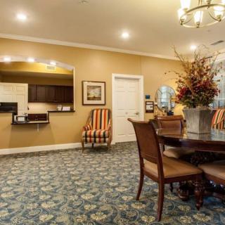 A cozy living space featuring a dining table, patterned carpet, and decorative flowers with warm lighting.