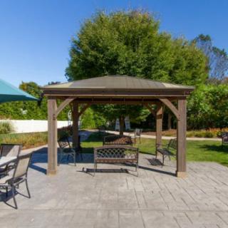 A sunny day in a backyard with a gazebo and patio furniture, including a swing.
