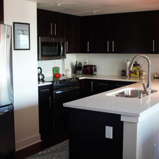 A modern kitchen with sleek black cabinets and stainless steel appliances.