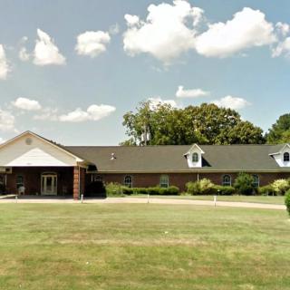 A suburban residential house with a large front lawn and clear skies.