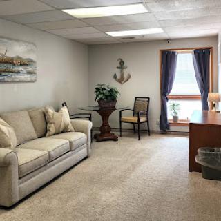 A cozy office lounge space featuring a comfortable sofa, a desk, and decorative elements.