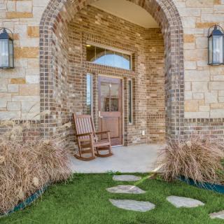 A welcoming front entrance with a brick facade, featuring a rocking chair on the porch and a stone pathway leading to the door.