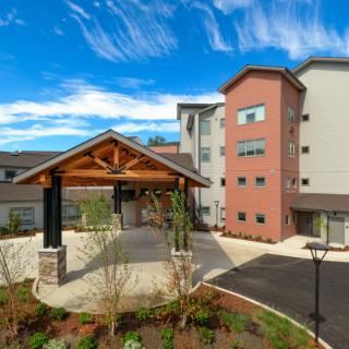 A modern residential building with a landscaped entrance and clear blue sky.