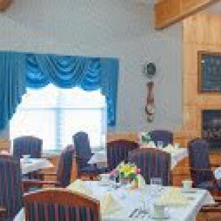 A cozy dining room with neatly arranged tables and elegant blue curtains.