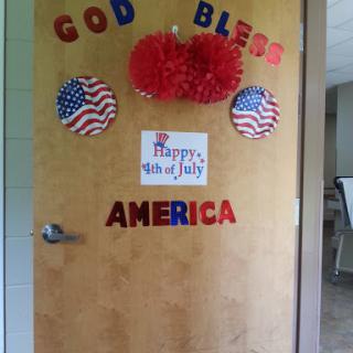 A patriotic door decoration celebrating July 4th with American flags and festive colors.