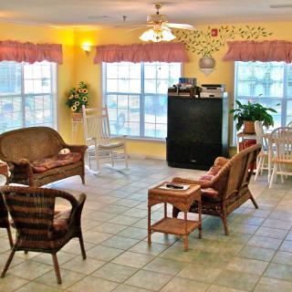 A cozy living room with wicker furniture, a television, and large windows letting in natural light.