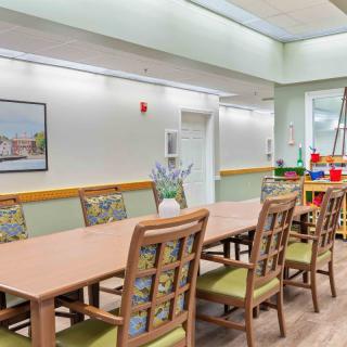 A spacious and well-lit dining area with a long table and multiple chairs, featuring modern decor.