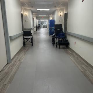 A spacious hospital hallway featuring wheelchairs along the side.
