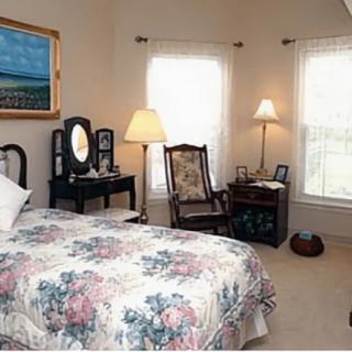 A cozy bedroom featuring vintage furniture, floral bedding, and soft natural light streaming through the windows.