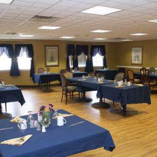 A spacious dining room with tables covered in blue tablecloths, set for a meal.