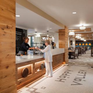 A welcoming hotel lobby with guests checking in at the reception desk, featuring warm wooden accents and ambient lighting.